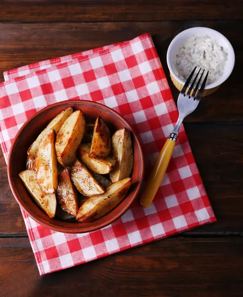 Gebakken aardappelen in kom en saus op tafel close-up — Stockfoto
