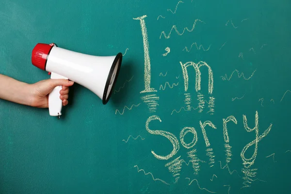 Hand holding megaphone on blackboard background — Stock Photo, Image