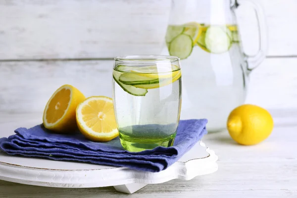 新鲜的柠檬和黄瓜木制背景上的玻璃器皿中水 — 图库照片
