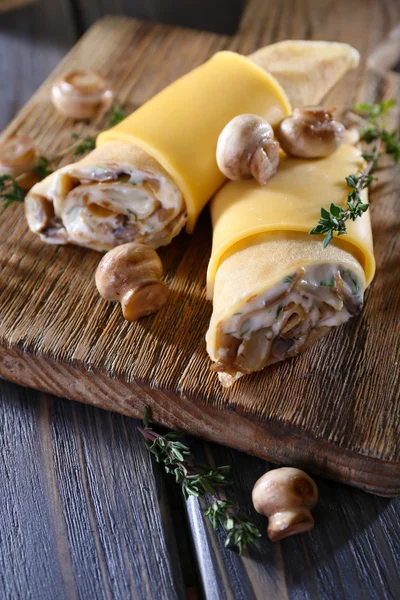 Pfannkuchen mit cremigen Pilzen auf Schneidebrett auf Holztisch, Nahaufnahme — Stockfoto