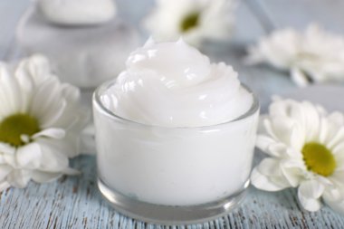 Çiçek ve spa taşlar ahşap arka plan üzerinde kozmetik krem