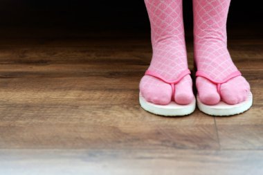 Kat zemin üzerine pembe parmak arası terlik ile çoraplı kadın ayakları
