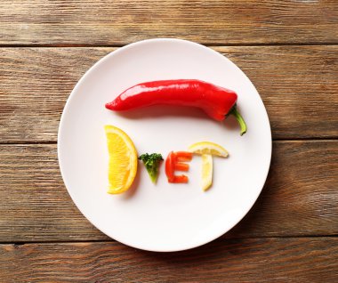 Beyaz ahşap masa, üstten görünüm tabağa dilimlenmiş sebze kelime diyet yapılmış