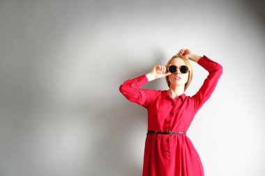 Kırmızı elbise ve gri arka plan üzerinde güneş gözlüğü ifade genç model