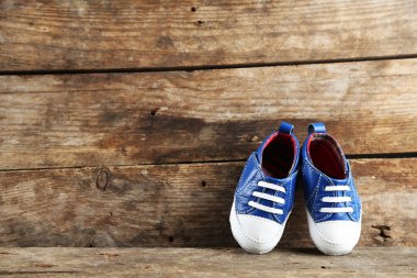ahşap arka plan üzerinde renkli yürümeye başlayan çocuk ayakkabı