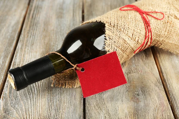 Botella de vino envuelta en tela de arpillera sobre tablones de madera fondo —  Fotos de Stock