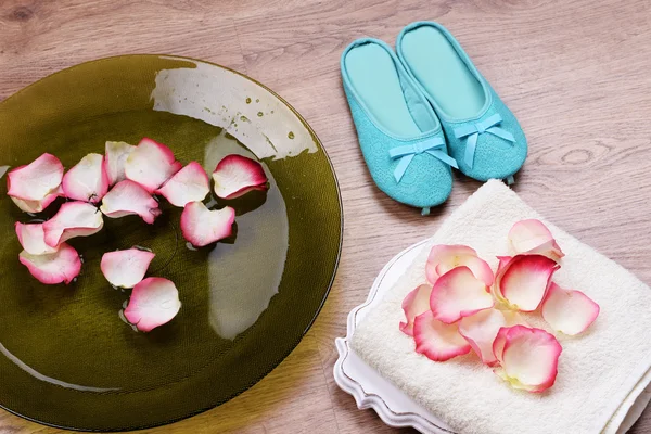 Spa kom met water, rozenblaadjes, handdoek en slippers op lichte achtergrond. Concept van pedicure of natuurlijke spa-behandeling — Stockfoto