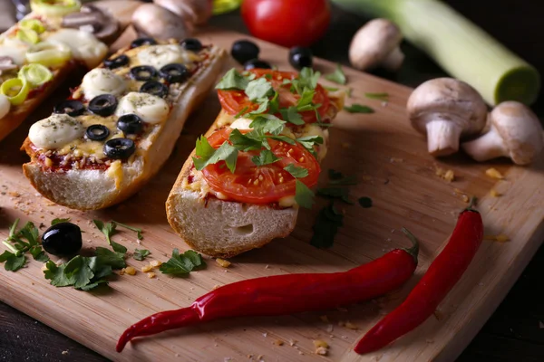 Different sandwiches with vegetables and cheese on cutting board on table close up — Stock Photo, Image