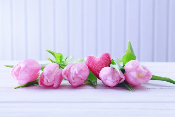 Hermosos tulipanes rosados con corazón decorativo sobre fondo de madera —  Fotos de Stock