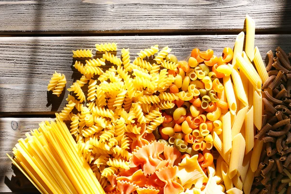 Different types of pasta on wooden planks background — Stock Photo, Image