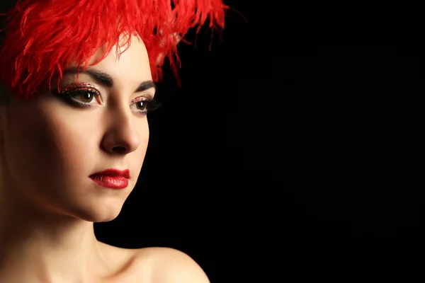暗い背景にキラキラ派手なメイクや赤羽を持つ美しい女性の肖像画 — ストック写真