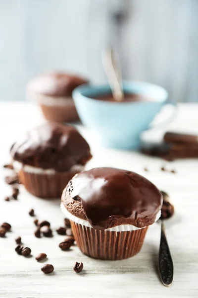 Leckere hausgemachte Schokoladenmuffins und Tasse Kaffee auf Holztisch, auf hellem Hintergrund — Stockfoto