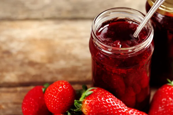 Vasi di marmellata di fragole con bacche su sfondo di legno — Foto Stock