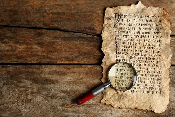Grunge paper with hieroglyphics with magnifier on wooden background — Stock Photo, Image