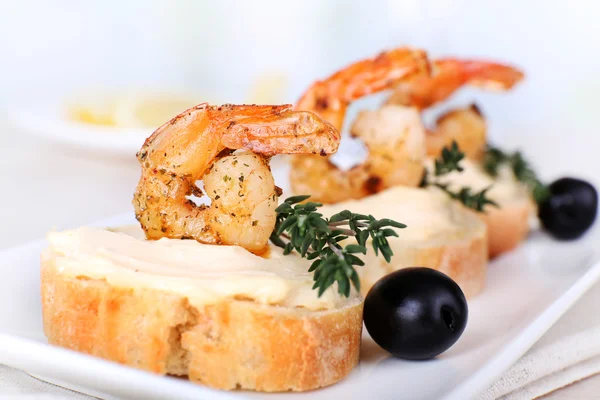 Appetizer canapé com camarão e azeitonas na mesa sobre fundo claro — Fotografia de Stock