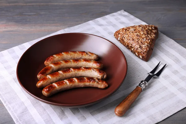 Grillwürste auf dem Teller mit Brot auf dem Tisch aus nächster Nähe — Stockfoto