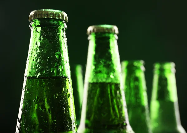 Glazen flessen bier op donkere groene achtergrond — Stockfoto