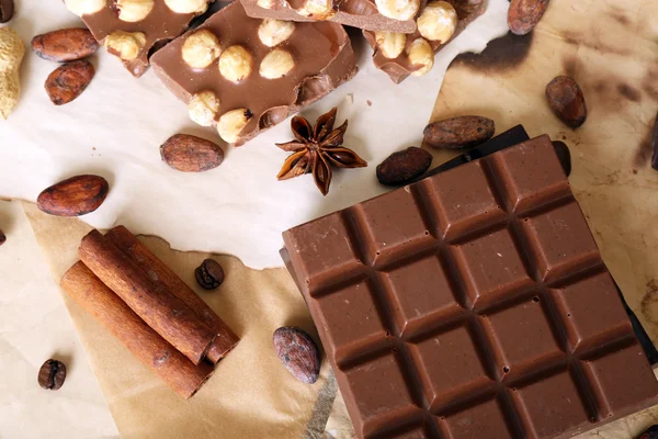 Cokelat dengan kacang dan rempah-rempah di atas kertas, closeup — Stok Foto