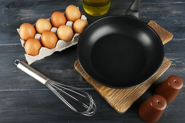 Still life with eggs and pan on wooden background — Stock Photo, Image