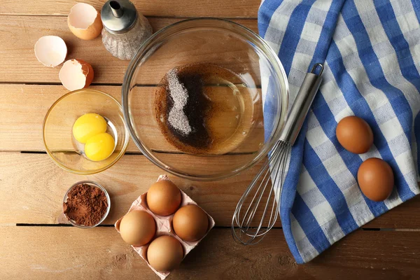 Приготування вершків з яйцями в скляній мисці на дерев'яному фоні — стокове фото