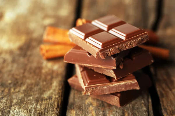 Pedazos de chocolate con palitos de canela sobre fondo de madera —  Fotos de Stock