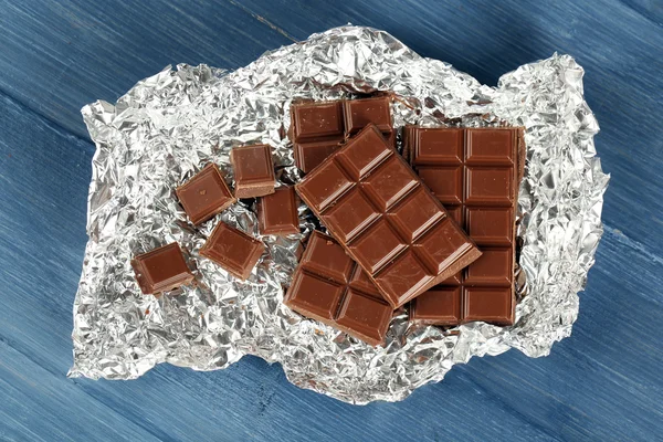 Chocolate en papel de aluminio sobre mesa de madera, primer plano —  Fotos de Stock