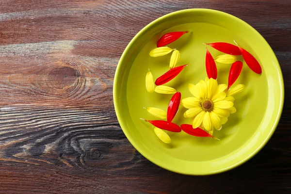 Pétalos de flores en cuenco verde, primer plano, sobre fondo de mesa de madera — Foto de Stock