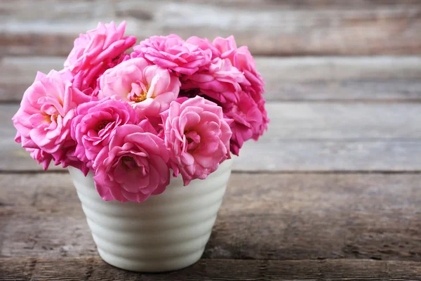 Vacker rosa rosor i kruka på trä bakgrund — Stockfoto