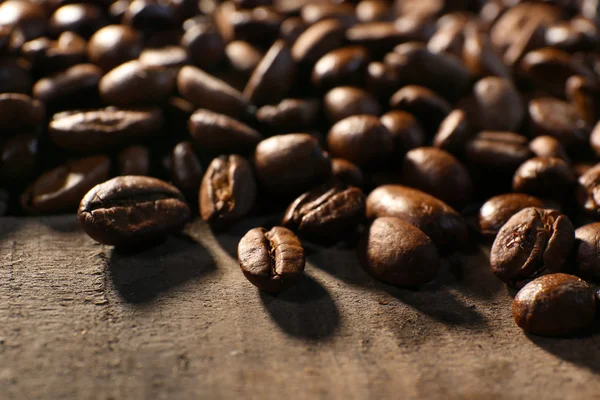 Montón de granos de café en la mesa de madera, primer plano — Foto de Stock