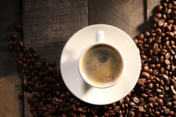 Xícara de café com grãos na mesa de madeira, vista superior — Fotografia de Stock