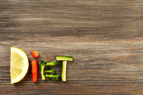 Slovo dieta z nakrájené zeleniny na dřevěné pozadí — Stock fotografie