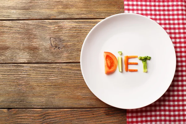 Word DIET en tranches de légumes dans une assiette blanche avec serviette sur fond en bois — Photo