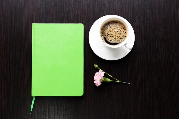 Kopp kaffe med anteckningsboken och färska blommor på träbord bakgrund — Stockfoto