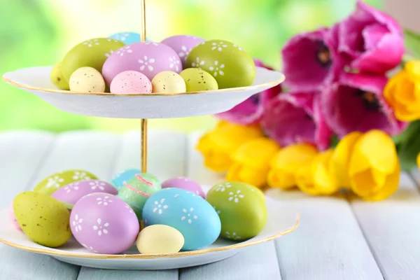 Huevos de Pascua sobre jarrón y tulipanes sobre mesa sobre fondo natural —  Fotos de Stock