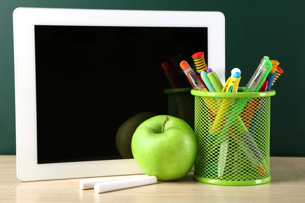 Digitales Tablet, bunte Stifte und Apfel auf dem Schreibtisch vor der Tafel — Stockfoto