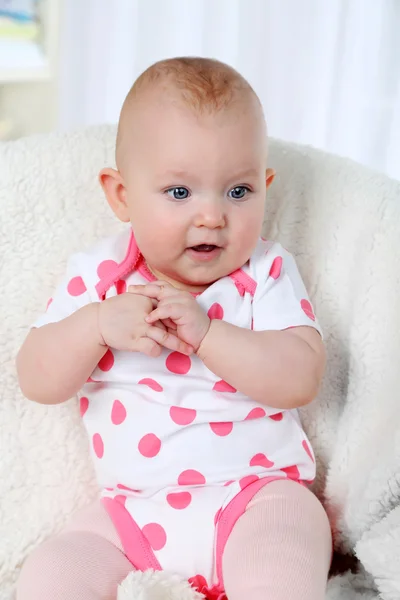 Cute baby girl sitting in arm-chair, on home interior background — Stock Photo, Image