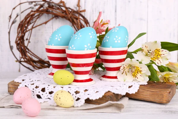 Composizione pasquale con uova e fiori pasquali, su sfondo ligneo — Foto Stock