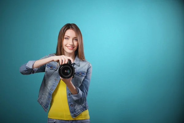 Young female photographer taking photos on blue background — Stock Photo, Image