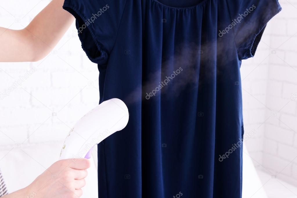 Women steaming dress in room
