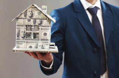 Ev modeli gri arka plan üzerinde erkek elinde para yaptı