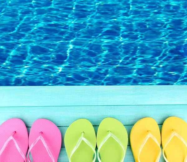 Colored flip flops on wooden platform beside sea — Stock Photo, Image
