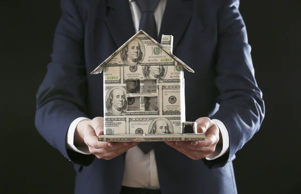 Model of house made of money in male hand, close up — Stock Photo, Image