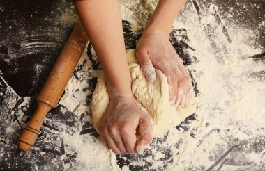 Making dough by female hands on wooden table background clipart