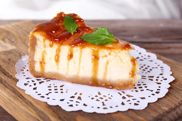 Cheese cake on paper napkin on cutting board on wooden table on light background — Stock Photo, Image