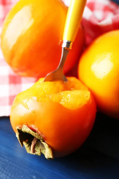 Ripe persimmons on color wooden background — Stock Photo, Image