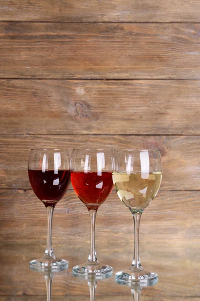 Different glasses of wine on table on wooden background — Stock Photo, Image