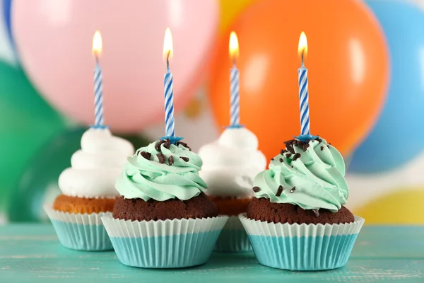 Deliciosos cupcakes de aniversário na mesa em fundo brilhante — Fotografia de Stock