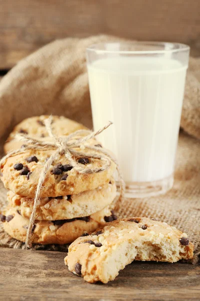 Leckere Plätzchen und ein Glas Milch auf rustikalem Holzgrund — Stockfoto