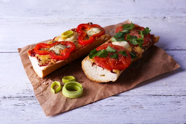 Sabroso sándwich con verduras y queso sobre papel sobre fondo de madera — Foto de Stock