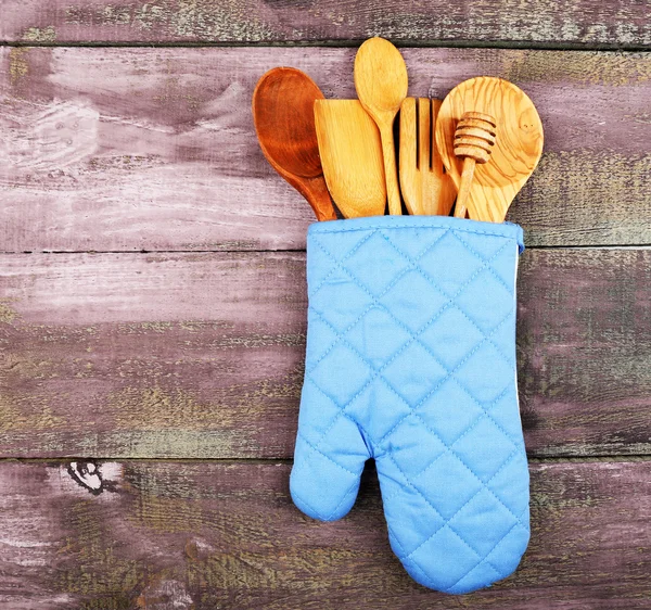 Different kitchen utensils in potholder on wooden background — Stock Photo, Image